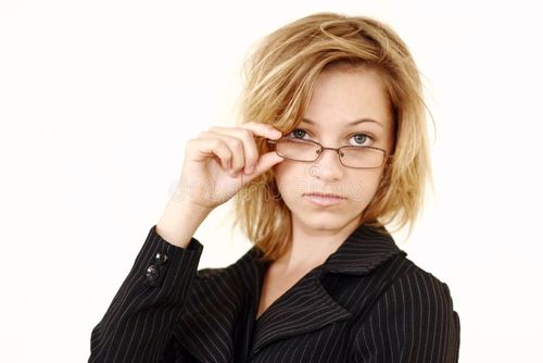 A portrait of a young professional woman with dark striped top, tipping her glasses down slightly to look over them. White background. Professional woman stock images, royalty-free photos and pictures