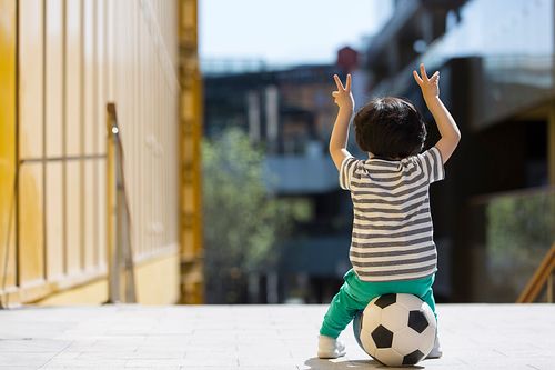 小男孩坐在足球上休息图片下载