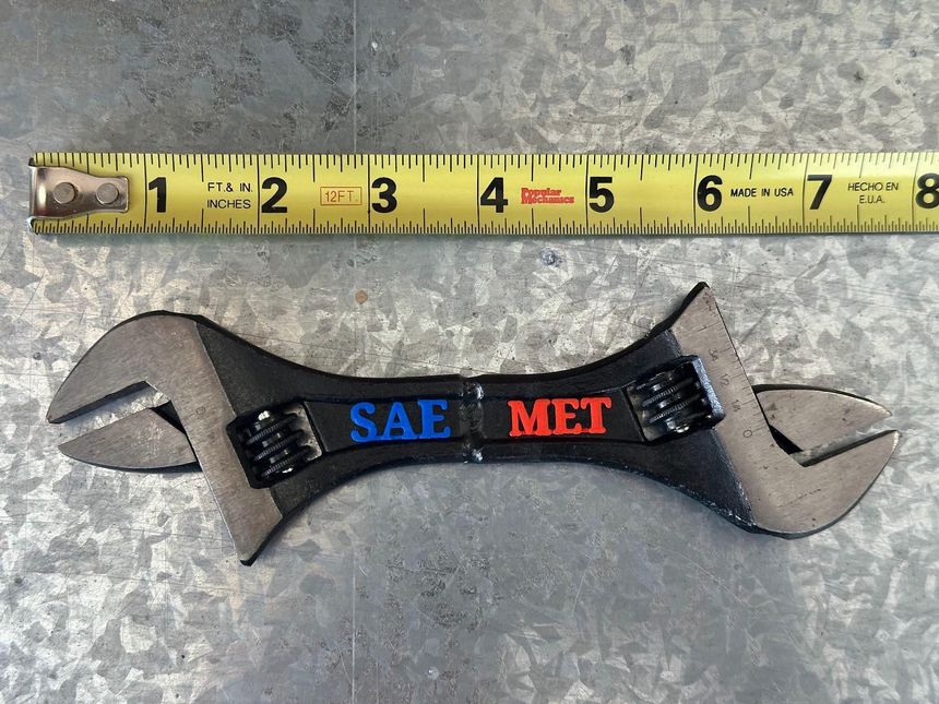 a wrench with the words safe met on it next to a measuring tape measure