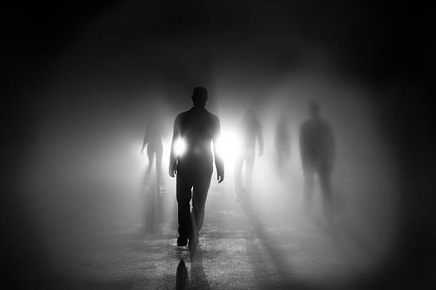 siluetas de personas caminando hacia la luz - silueta negra fotografías e imágenes de stock