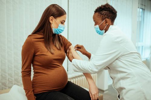 african american female doctor preparing a pregnant woman for vaccination - pregnancy medicine stock pictures, royalty-free photos & images