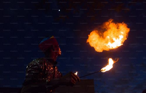 A man holding a lit stick in front of a fire