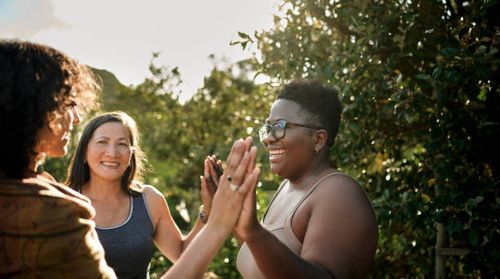 Women smiling during an exercise outside at a scenic wellness retreat Laughing woman and a group of other women standing with her hands together during an exercise at a wellness retreat in summer support stock pictures, royalty-free photos & images