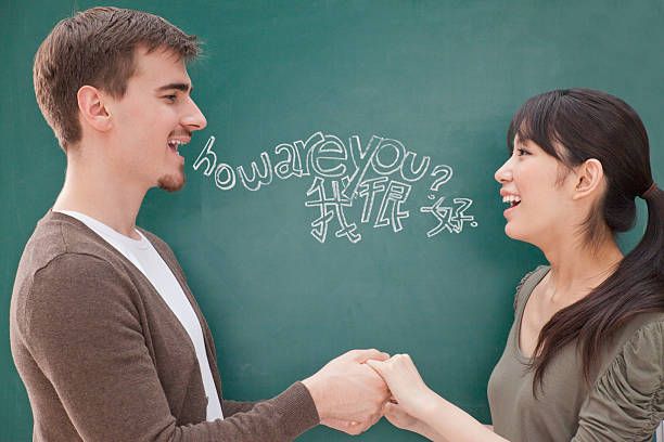 portrait of smiling male teacher and student in front of chalkboard holding hands - bilingue - fotografias e filmes do acervo