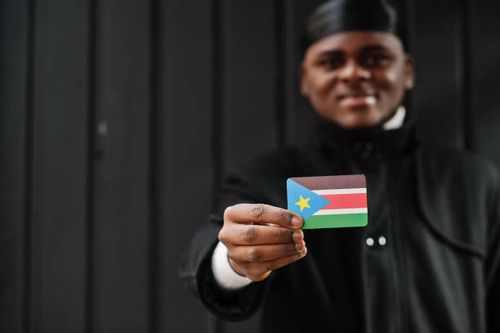 African man wear black durag hold South Sudan flag at hand isolated dark background. African man wear black durag hold South Sudan flag at hand isolated dark background. wau stock pictures, …