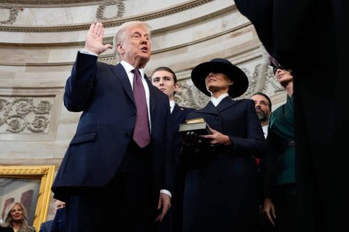 President-elect Donald Trump takes the oath of office from Chief Justice John Roberts as Barron Trump and Melania Trump look on during inauguration...