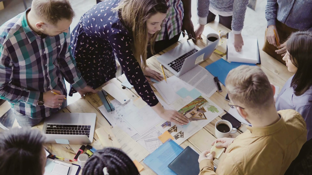 Top view of young team working on architectural project. Group of mixed race people standing ...