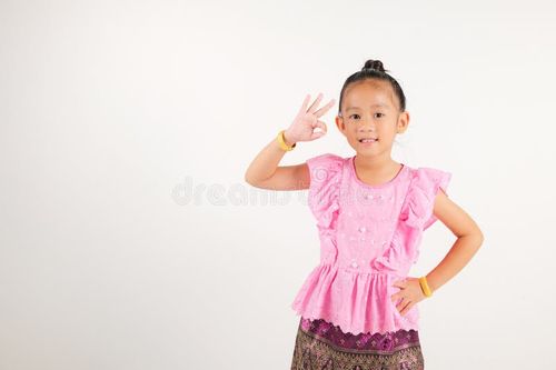 Portrait Thailand kid girl smiling traditional Thai dress costume showcases OK sign with smile, conveying agreement and positivity, studio isolated white background, kindergarten child success sign. Thai girl stock images, royalty-free photos and pictures