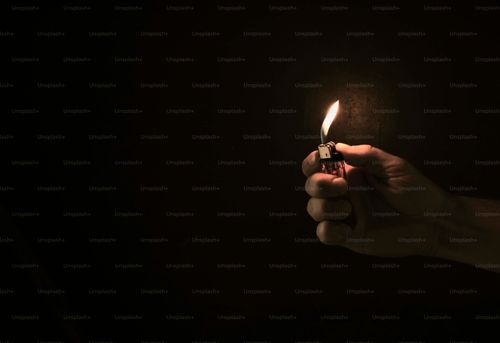 Hand holding lit lighter in the dark