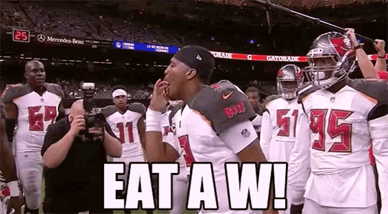 a group of football players are standing on a field with the words `` eat a w '' written on it .
