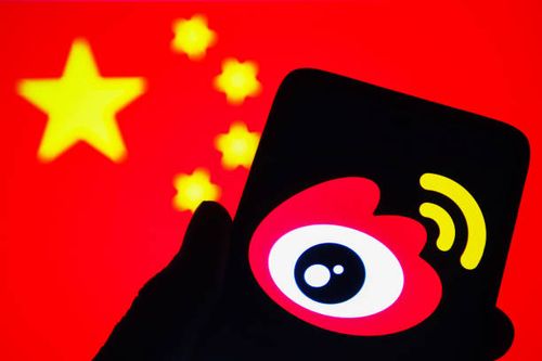 In this photo illustration, the logo of the Weibo logo, a Chinese social media platform is seen on a smartphone with a flag of China in the...