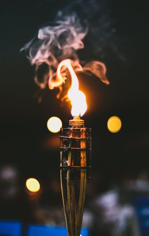 Free Close-up of a torch flame with a blurred bokeh background, creating a warm, dramatic effect. Stock Photo