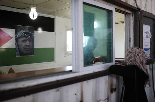 Portrait of late Palestinian leader Yasser Arafat above his national flag adorns a passport control station held by the Palestinian Authority at the...