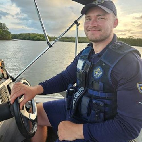 Paul Gibson steering a boat with mangroves in the background