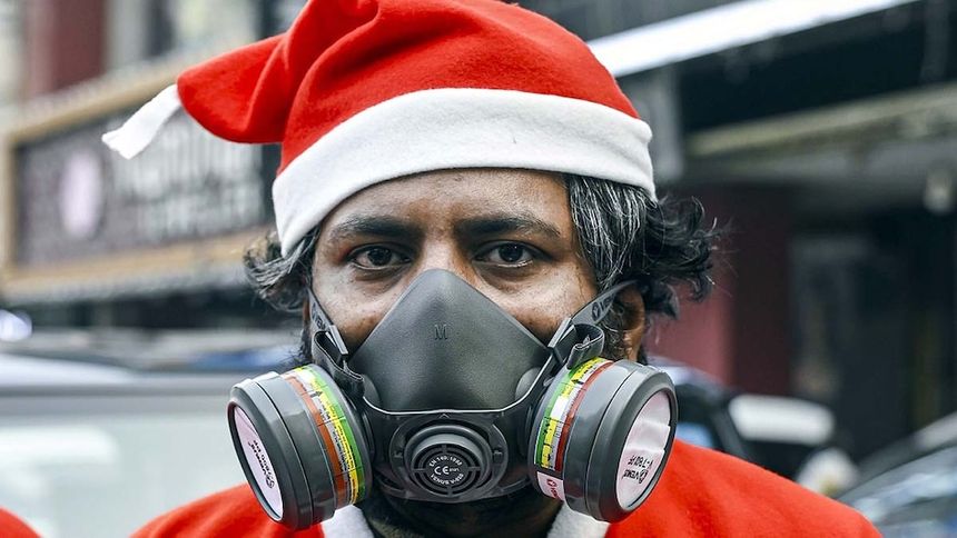 दिल्ली में सैंटा क्लॉज बनकर वायु प्रदूषण के खिलाफ मास्क पहनकर विरोध करता एक युवक. (Photo: PTI)