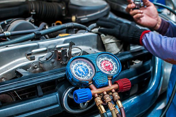 Automotive technician checking vehicle air conditioning system with pressure gauges at Tuttle-Click Tustin Chrysler Jeep Dodge Ram