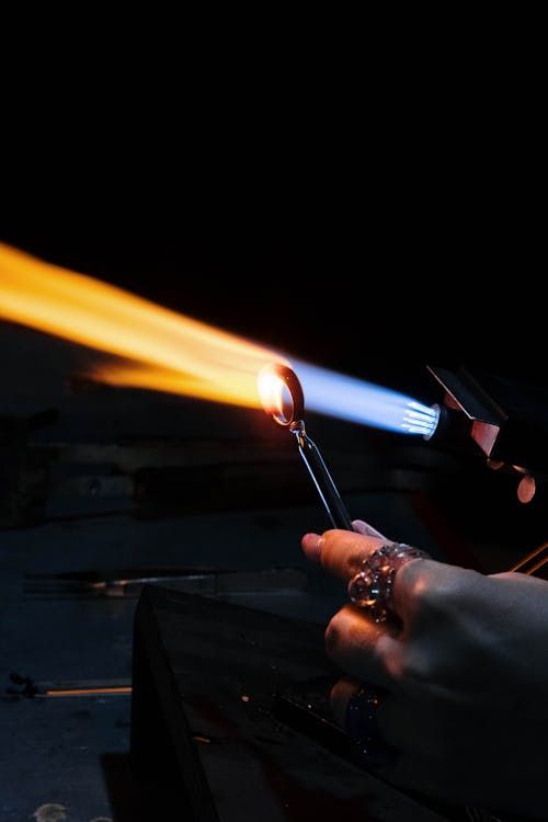 Free Close-up of an artisan glass blower manipulating molten glass with a torch. Stock Photo