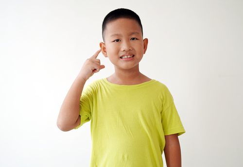 孩子的手指指向自己的耳朵，纯色背景与复制空间图片下载