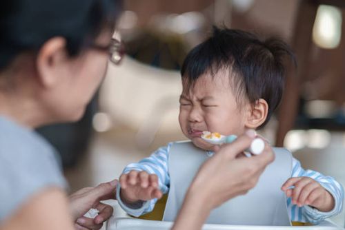 cute baby boy refusing to eat food and crying while his mother feeds him. - person refusing food stock pictures, royalty-free photos & images