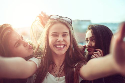 group of smiling girls taking funny selfie outdoors at sunset - funny face selfie stock pictures, royalty-free photos & images