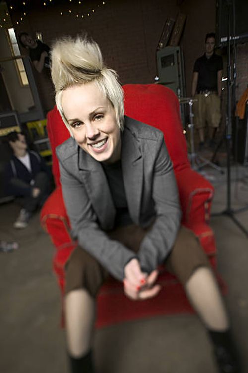 lifestyle portrait of a teenage blonde female as she sits in a chair with her friends behind her - she stock pictures, royalty-free photos & images