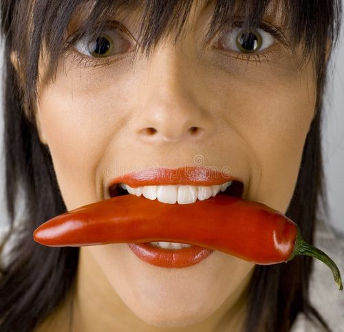 Closeup of woman's face. She's holding red pepper using her teeth. Shes stock images, royalty-free photos and pictures