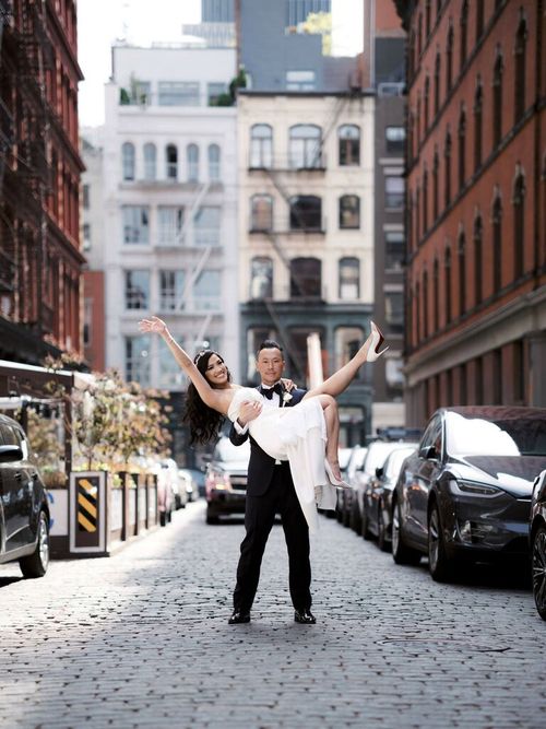 Cute Couple Poses: Husband holds his wife whlie she poses on a city street.