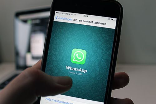 Free A smartphone displaying the WhatsApp application screen held by a person. Stock Photo