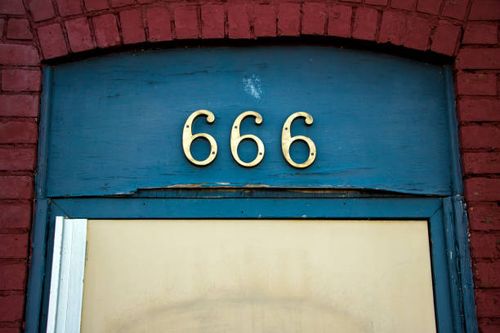 Street number 666 above a doorway The brass street address number '666' above a doorway on blue painted wood, framed by red brick. number 666 stock pictures, royalty-free photos & images